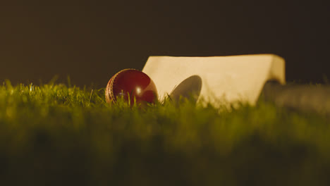 Studio-Cricket-Still-Life-With-Close-Up-Of-Bat-And-Ball-Lying-In-Grass