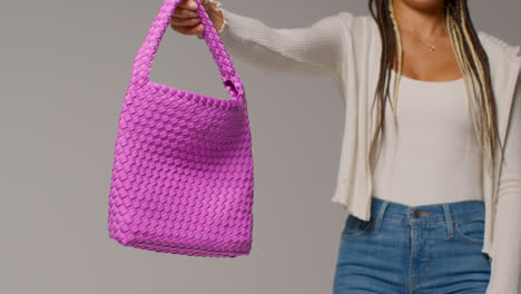 Close-Up-Of-Female-Social-Media-Influencer-Producing-User-Generated-Content-Holding-Out-Purple-Fashion-Bag-1