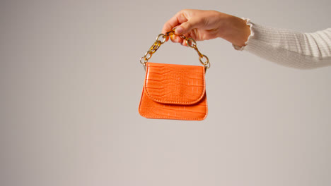 Close-Up-Of-Female-Social-Media-Influencer-Producing-User-Generated-Content-Holding-Out-Orange-Fashion-Handbag-4