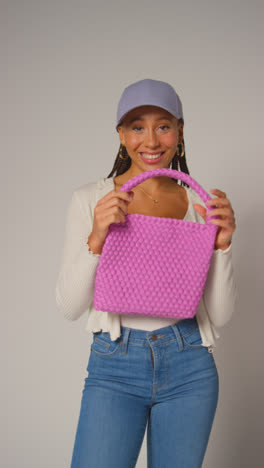 Vertical-Video-Of-Female-Social-Media-Influencer-Producing-User-Generated-Content-In-Studio-Catching-And-Modelling-Purple-Bag