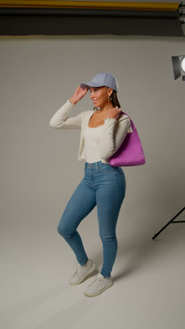 Vertical-Video-Of-Female-Social-Media-Influencer-Producing-User-Generated-Content-In-Studio-Catching-And-Modelling-Purple-Bag-1