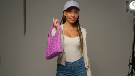 Female-Social-Media-Influencer-Producing-User-Generated-Content-In-Studio-Holding-Variety-Of-Different-Fashion-Handbags-1