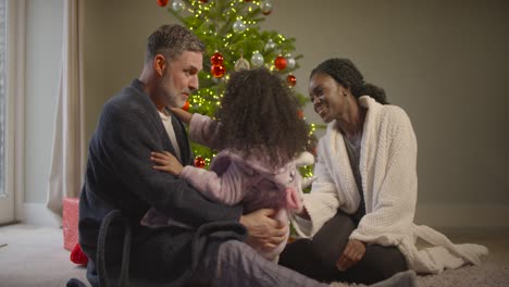 Familia-sentada-alrededor-del-árbol-de-navidad
