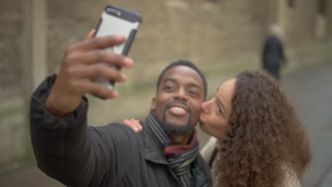 Woman-Kisses-Man-on-Cheek-for-Selfie