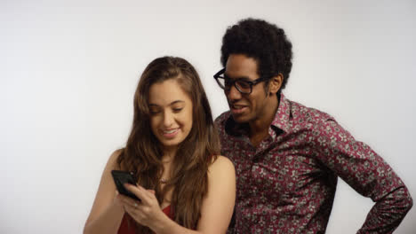 Smiling-Couple-Look-at-Photos-on-Phone