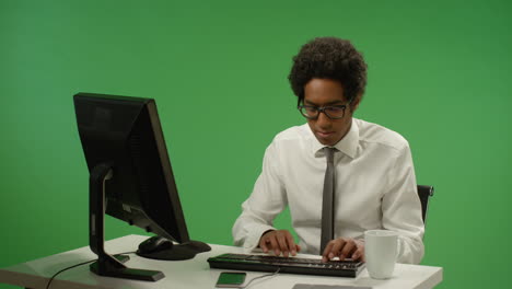 Hombre-de-negocios-sentado-en-el-escritorio-escribiendo-en-pantalla-verde
