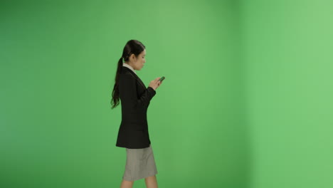 Businesswoman-texting-while-walking-on-green-screen