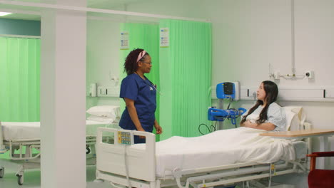 Female-Nurse-Chatting-to-Patient-in-Hospital-Bed