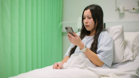 Female-Hospital-Patient-in-Bed-Picks-Up-Teléfono