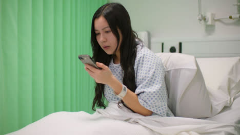 Female-Hospital-Patient-Sits-Up-and-Uses-Phone