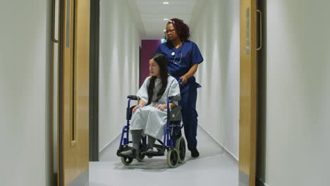 Female-Nurse-Pushes-Patient-In-Wheelchair