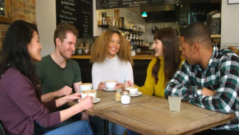 A-group-of-friends-socialising-around-table-in-cafe