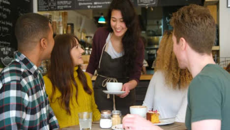 Friends-Socialising-In-Cafe-Being-Served-By-Waitress