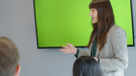 Businesswoman-Presenting-To-Colleagues-Using-Green-Screen-Tv