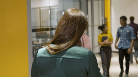 Rear-View-Businesswoman-Talking-On-Smartphone-In-Corridor