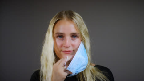 Young-Blonde-Woman-Removes-Face-Mask-Smiles