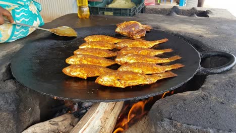 Spicy-fishes-being-fried-in-big-cast-iron-pan-in-road-side-eatery-Hogenakkal-Tamil-Nadu-India