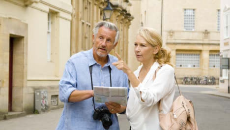 Tracking-Shot-of-Middle-Aged-Tourist-Couple-Reading-Map