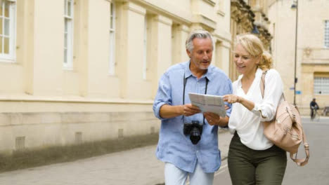 Tracking-Shot-of-Middle-Aged-Tourist-Couple-Reading-Map-Together