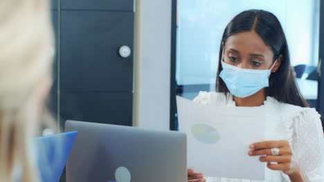Over-the-Shoulder-of-Woman-In-Face-Mask-Looking-at-Document-