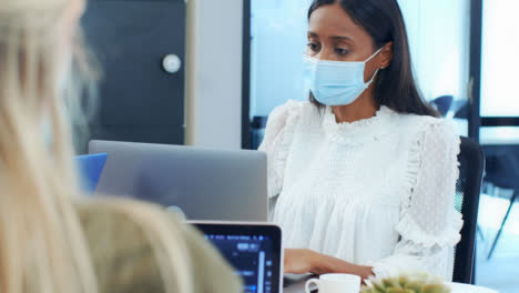 Over-the-Shoulder-of-Woman-In-Face-Mask-Looking-at-Laptop