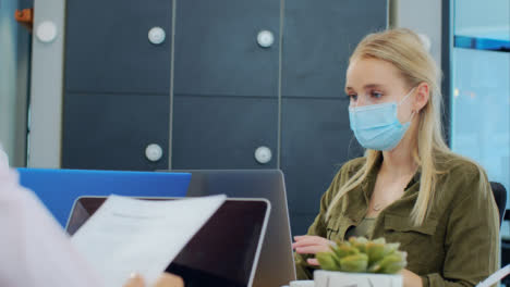 Over-the-Shoulder-Pan-of-Woman-In-Face-Mask-On-Laptop