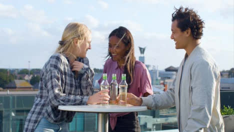 Medium-Shot-of-3-Friends-Enjoying-a-Drink-On-City-Rooftop