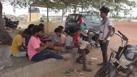 A-group-of-young-boys-singing-country-songs-and-playing-drums-under-a-tree