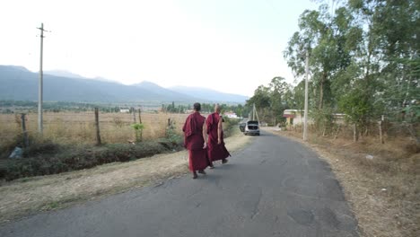 Kollegal,-Karnataka-/-India---March-14-2020:-Wide-angle-panning-shot-of-two-monks-walking-on-an-empty-road-with-beautiful-mountains-in-the-background-during-evening