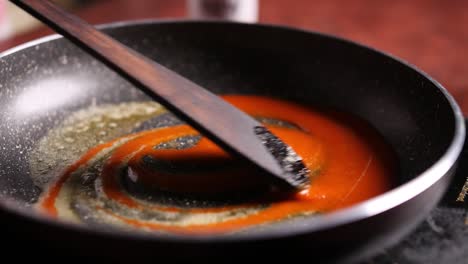 Slow-motion-closeup-of-red-sauce-and-butter-being-slowly-stirred-in-a-pan-with-wooden-spatula