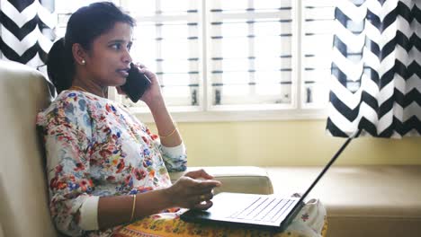 Closeup-of-an-Indian-business-woman-working-from-home-sitting-on-a-sofa-and-talking-on-phone-due-to-the-covid19-coronavirus-lockdown.