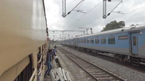 Vaniyambadi-Tamilnadu--India--December-14-2019-People-jumping-from-an-electric-train-and-dangerously-crossing-the-tracks-while-another-train-passes-at-high-speed-in-the-opposite-side