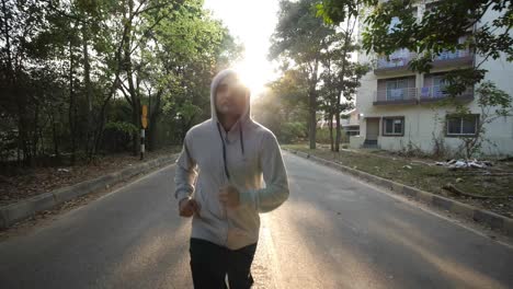 Closeup-of-an-adult-asian-man-wearing-a-hoodie-sweat-shirt-and-jogging-during-dawn