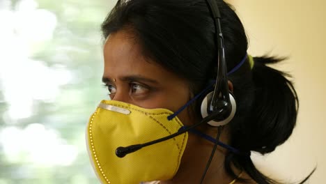 Closeup-of-an-Indian-origin-woman-wearing-protective-mask-and-headphone-mic-working-in-a-BPO-start-up-company-during-the-Covid19-corona-virus-pandemic