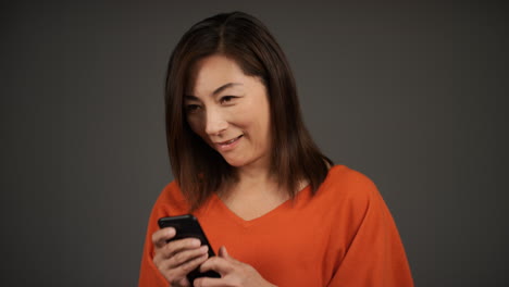 Middle-Aged-Woman-Smiling-and-Texting-On-Her-Phone-Portrait
