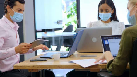 Three-Young-Colleagues-In-Face-Masks-Working-in-Modern-Office