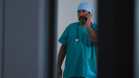 Middle-Aged-Surgeon-Having-Conversation-On-Mobile-Phone