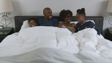 Parents-Young-Children-Snuggle-with-Them-In-Their-Bed