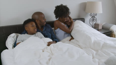 Middle-Aged-Parents-Children-Snuggling-In-Bed-with-Them-