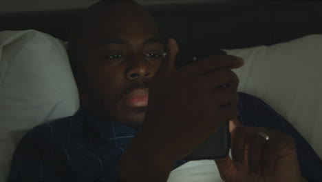 Middle-Aged-Man-Laying-In-Bed-Scrolling-On-Smartphone