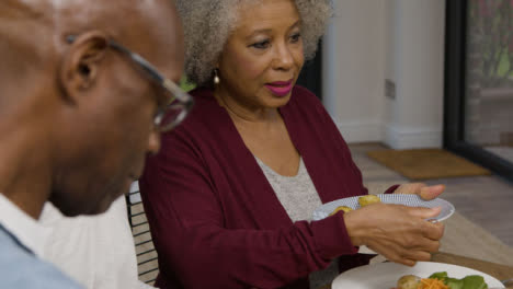 Miembro-Senior-De-La-Familia-Plateando-Patatas-Durante-La-Cena