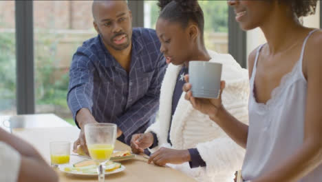 Family-Laughing-and-Talking-to-One-Another-Over-Breakfast-at-Kitchen-Island