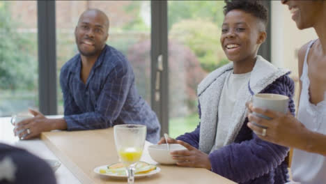 Young-Girl-Making-Her-Brother-and-Parents-Laugh-During-Breakfast