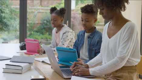 Madre-Trabajando-Desde-Casa-Mientras-Sus-Hijos-Adolescentes-Hacen-La-Tarea-Junto-A-Ella