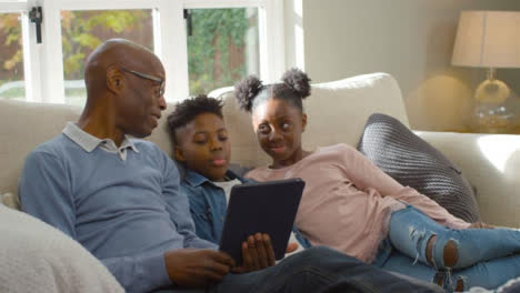 Grandfather-Reading-Story-to-Grandchildren-from-Electronic-Tablet