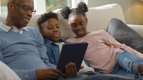 Grandfather-Reading-Story-to-His-Grandchildren-from-Electronic-Tablet