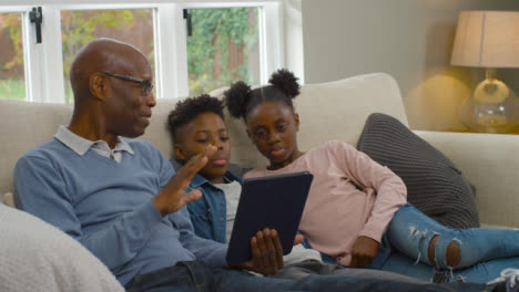 Grandfather-Reading-a-Story-to-Grandchildren-from-Electronic-Tablet