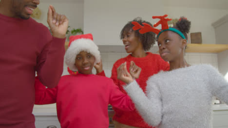 Joyful-Family-Dancing-Playfully-Together-During-Christmas-Video-Call-