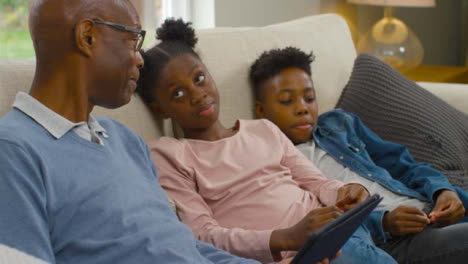 Grandfather-Reading-a-Story-On-an-Electronic-Tablet-to-Grandchildren