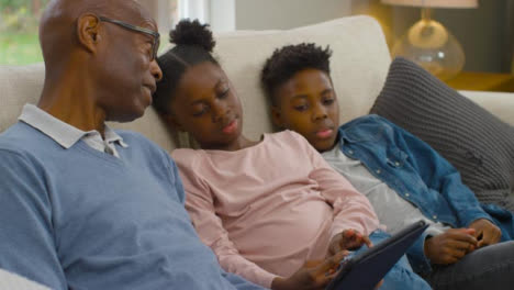 Grandfather-Reading-a-Story-On-an-Electronic-Tablet-to-Grandchildren